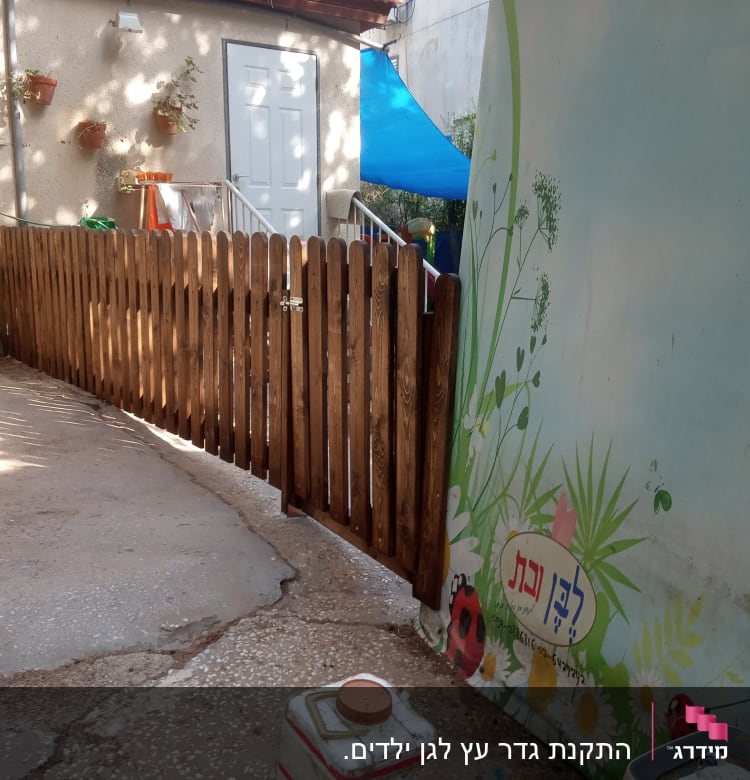 גדר עץ חומה בחצר עם קיר מעוטר בציורים